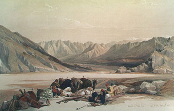Camels and drivers rest in the desert before beginning a steep climb.